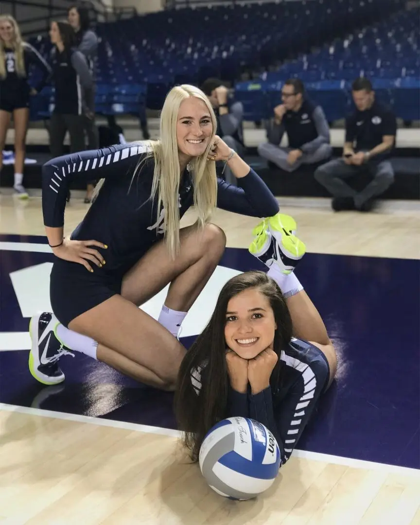 BYU volleyball girls in navy blue uniforms posing on a gym floor