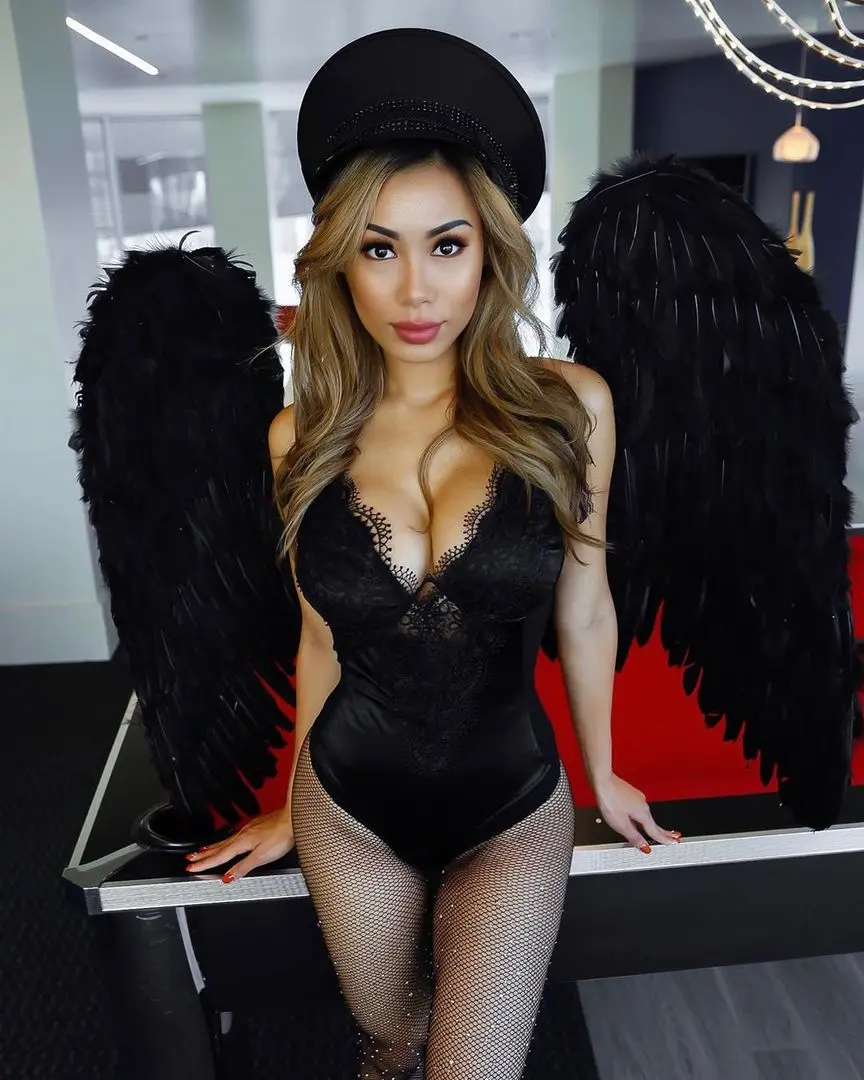 Jenna Kaey as a dark angel in a black lace bodysuit, fishnet stockings, black hat, and large black wings.