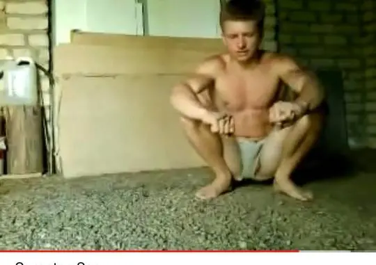 Muscular man in tiny white sexy shorts squatting on a gravel floor