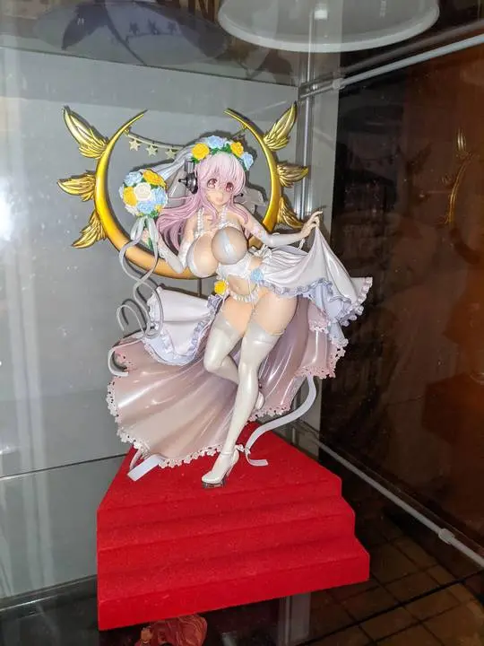 SuperSonico anime figure with long pink hair in a white frilled dress and flower crown on a red tiered stand