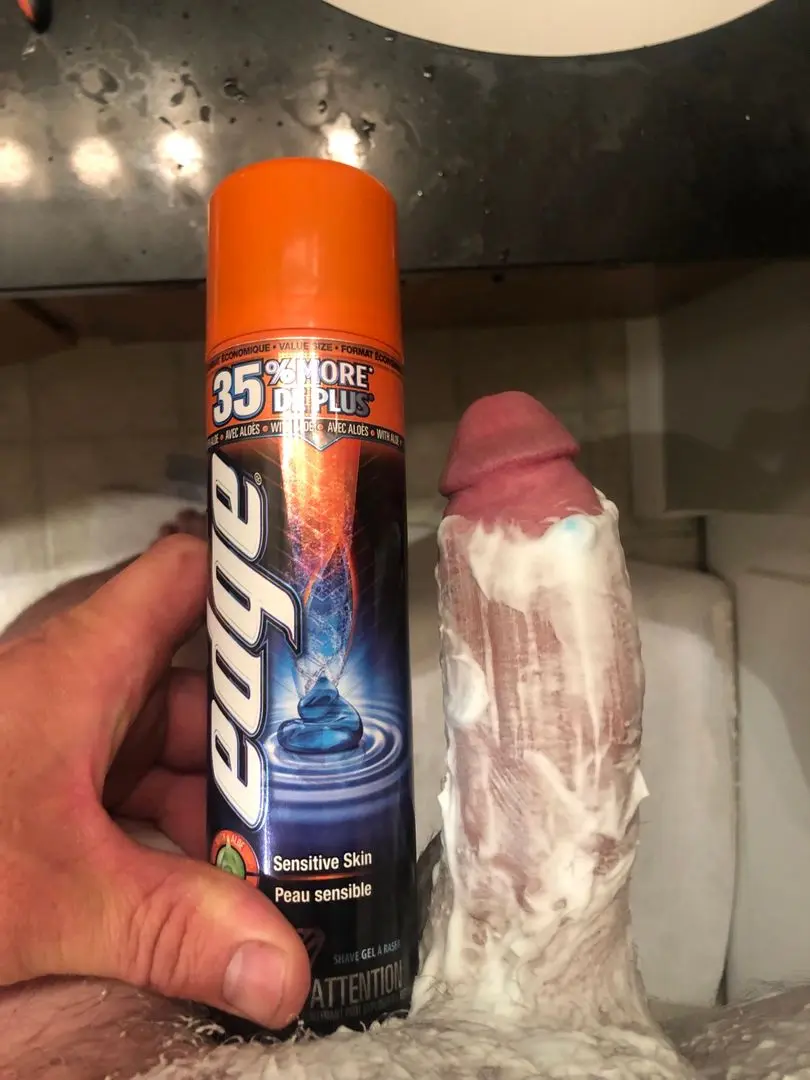Athletic white man pelfie in a bathroom, holding Edge shave gel next to his uncut penis covered in shaving cream.