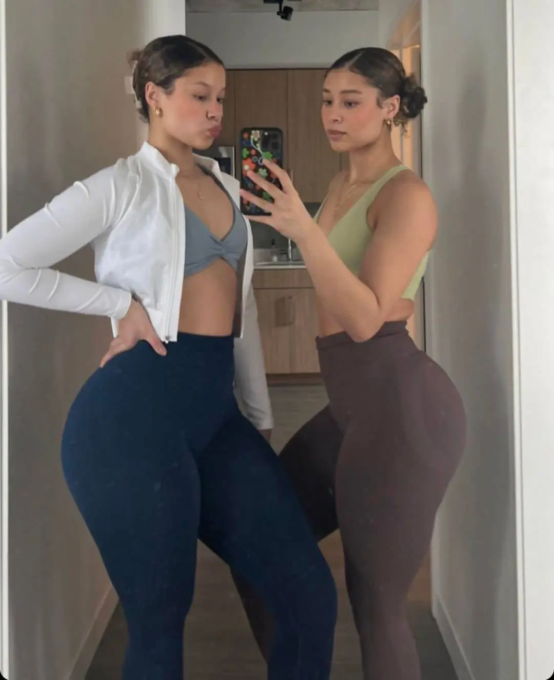 Lexie and Ana posing for a mirror selfie in athletic wear, including sports bras and leggings