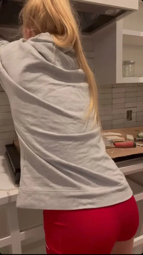 Holly Holm wearing a grey hoodie and red shorts standing in a kitchen