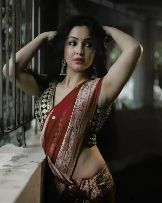Indian woman in a red and gold saree posing with arms up