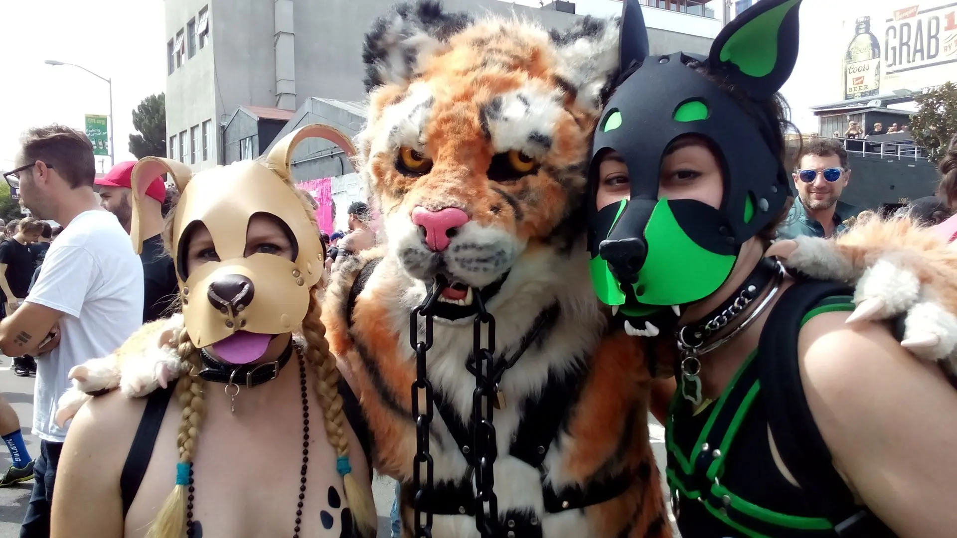 Kato and Pepper in pup play gear and masks at the Folsom Street Fair, including a man in a tiger costume.