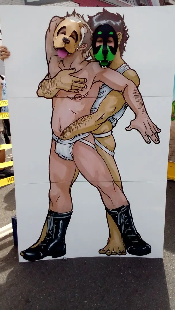 Kato and Pepper in pup play gear and masks at the Folsom Street Fair, including a man in a tiger costume.