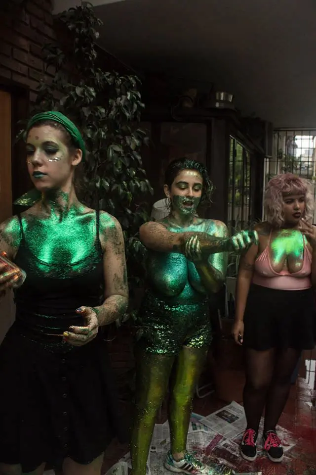 Athletic brunette woman in green goblin cosplay with body paint and glittery outfit