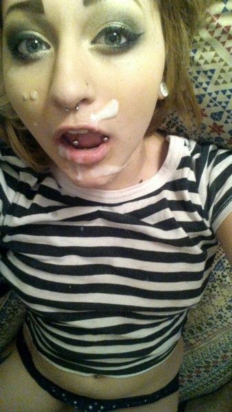 Slim blonde woman with a nose piercing in a striped shirt posing for a cum selfie