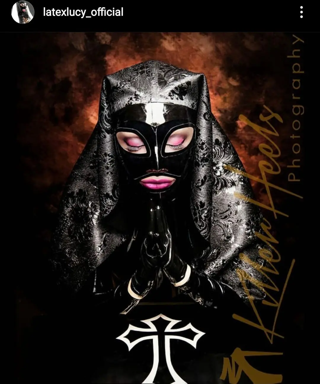 Latex Lucy in a black latex mask and silver patterned veil in a prayer pose for Rubber Religion.