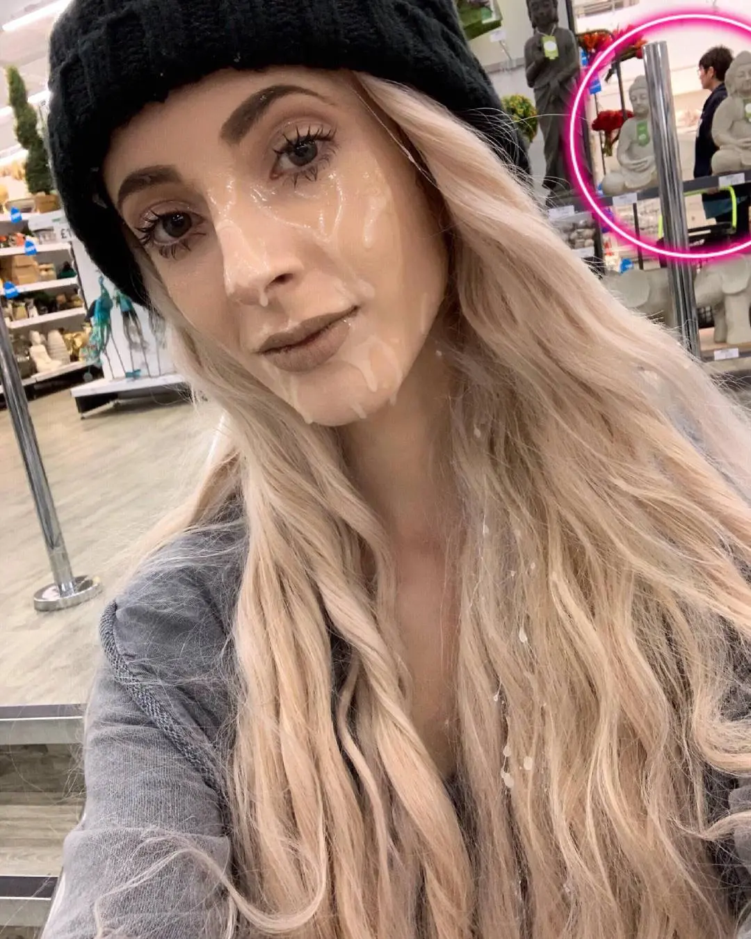 Slim white woman with long blonde hair and a black beanie posing for a public cumwalk selfie with a facial.