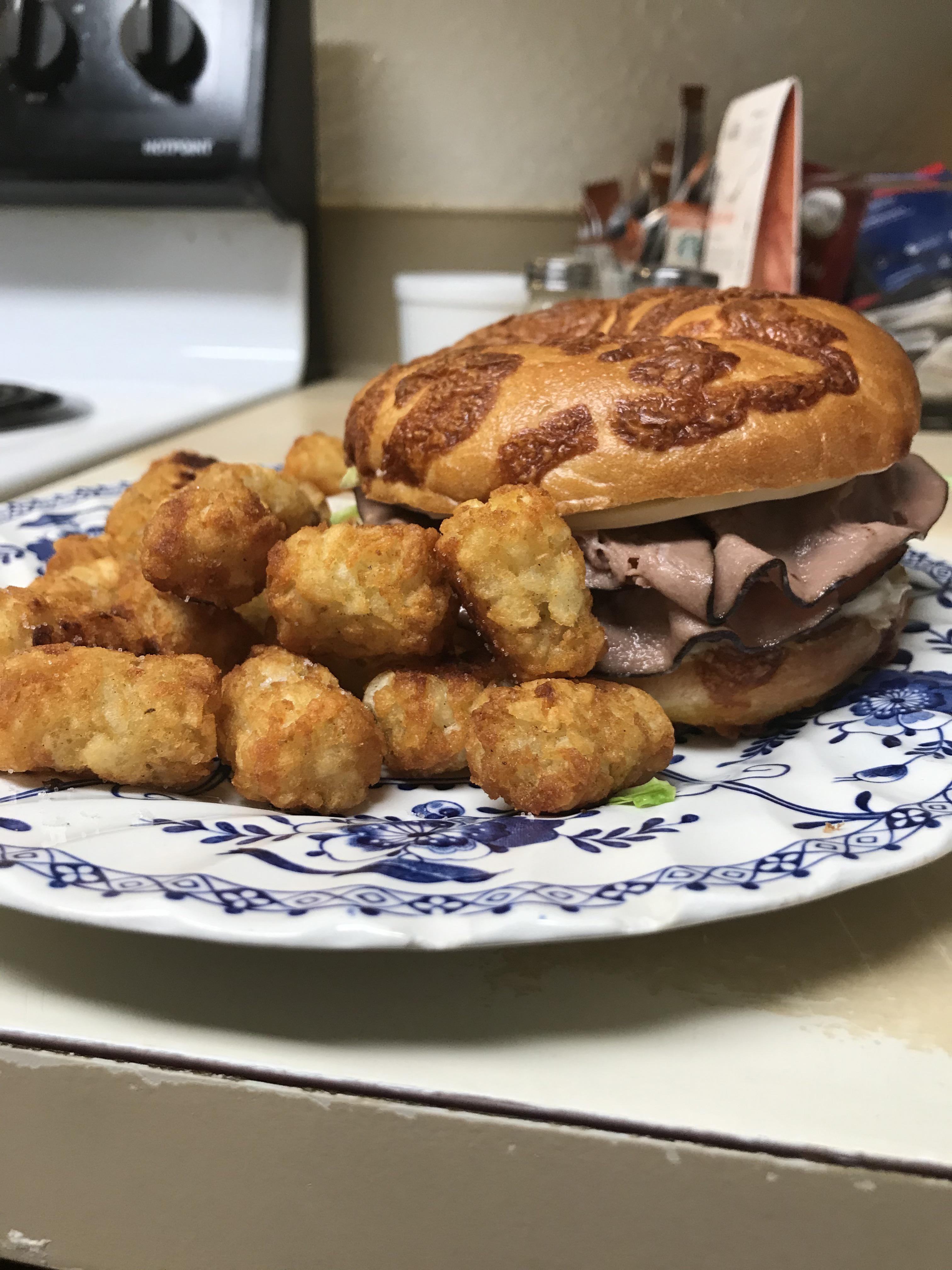 Roast beef and provolone sandwich on a cheese bagel with iceberg and brown mustard,