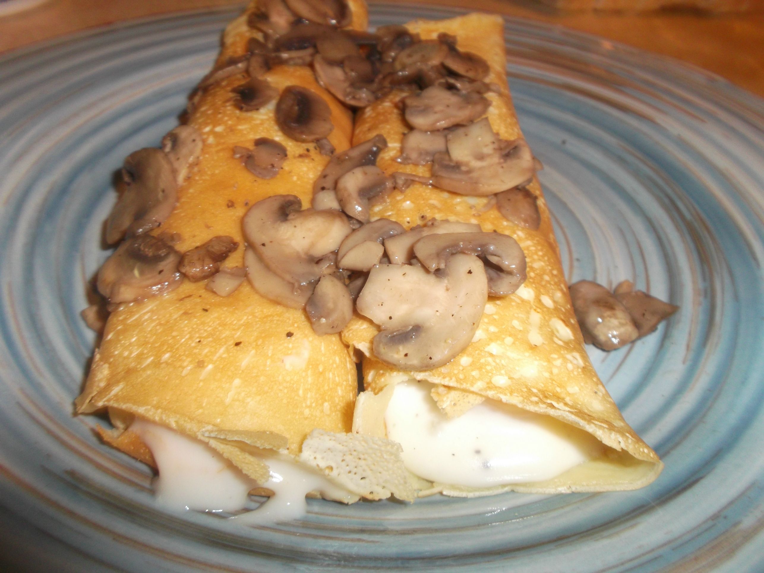 Savory crepes with shrimp and cream sauce topped with sauteed mushrooms