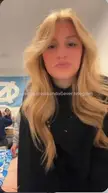 Slim white woman with long blonde hair in a black shirt taking a selfie