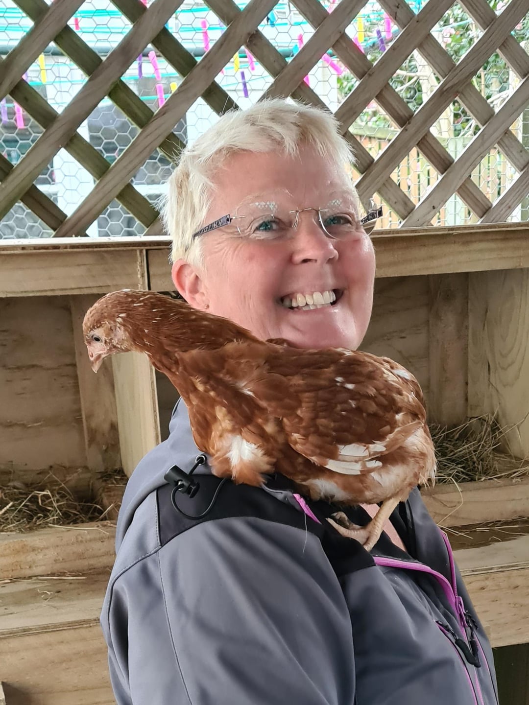 Joy Donaldson smiling with a brown chicken perched on her shoulder