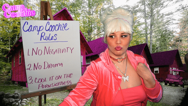 Kaceytron in a pink velour outfit standing by a Camp Coochie rules whiteboard in front of purple cabins