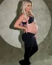 Alexa Bliss pregnant in black athletic wear, showing her baby bump in a side profile pose.