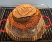 Homemade bread with a heart-shaped design on top, resting on a wire rack over a red pot