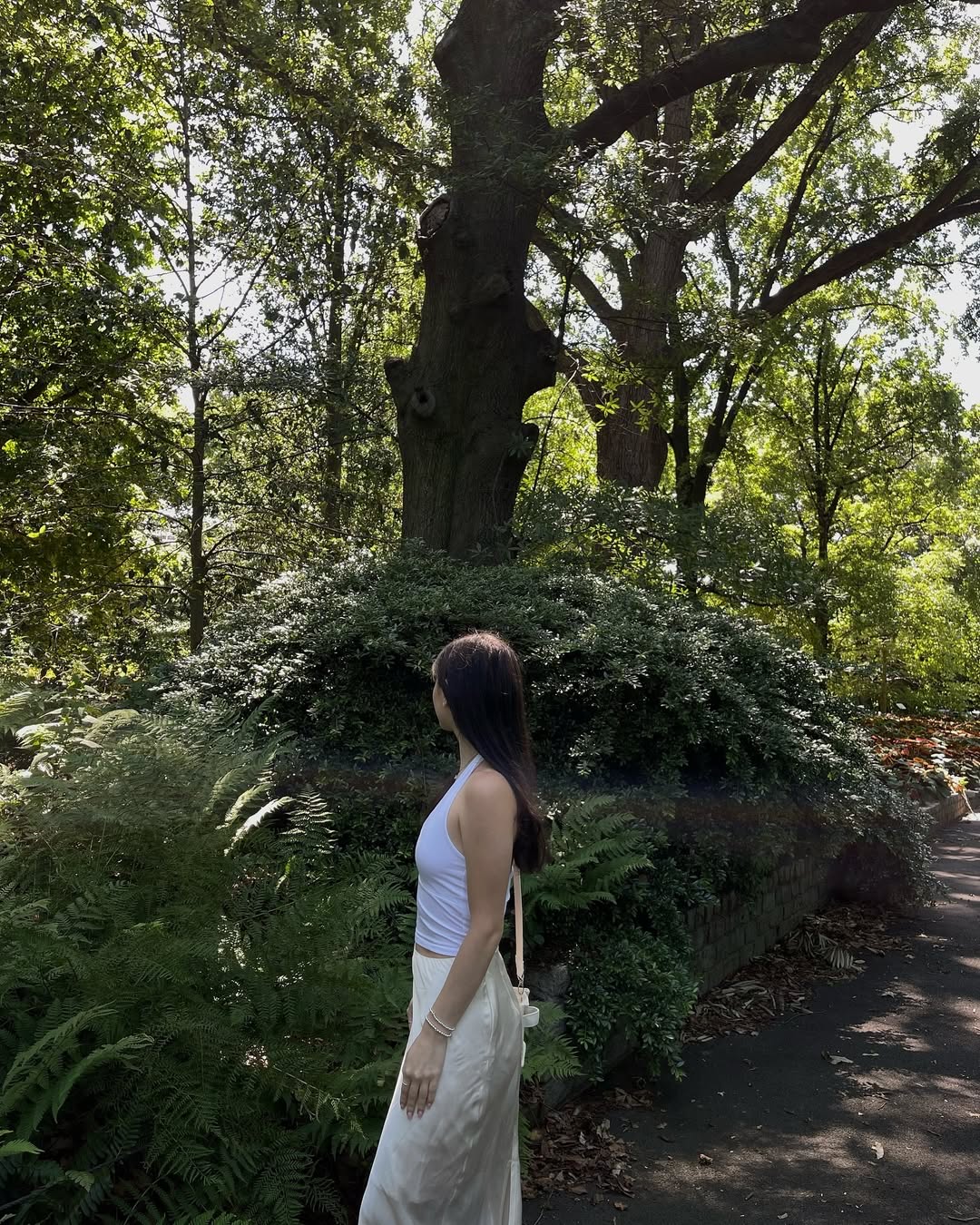 Skye ASMR posing in a sunny garden wearing a white halter top and beige skirt