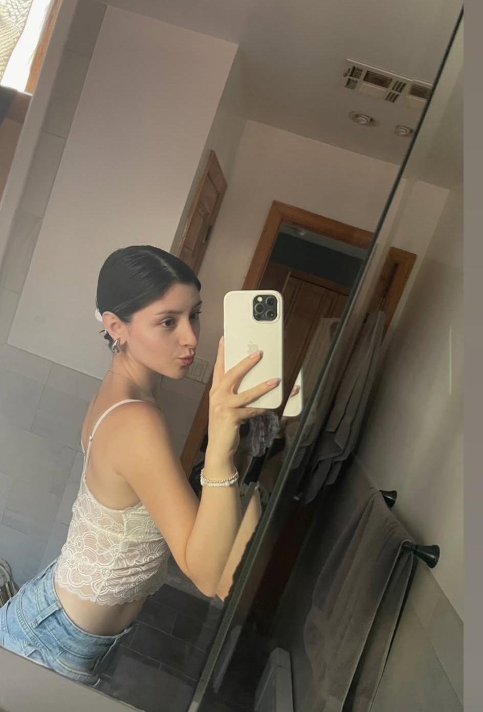 Skye ASMR posing in a sunny garden wearing a white halter top and beige skirt