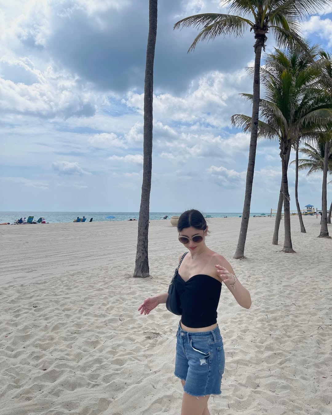Skye ASMR posing in a sunny garden wearing a white halter top and beige skirt