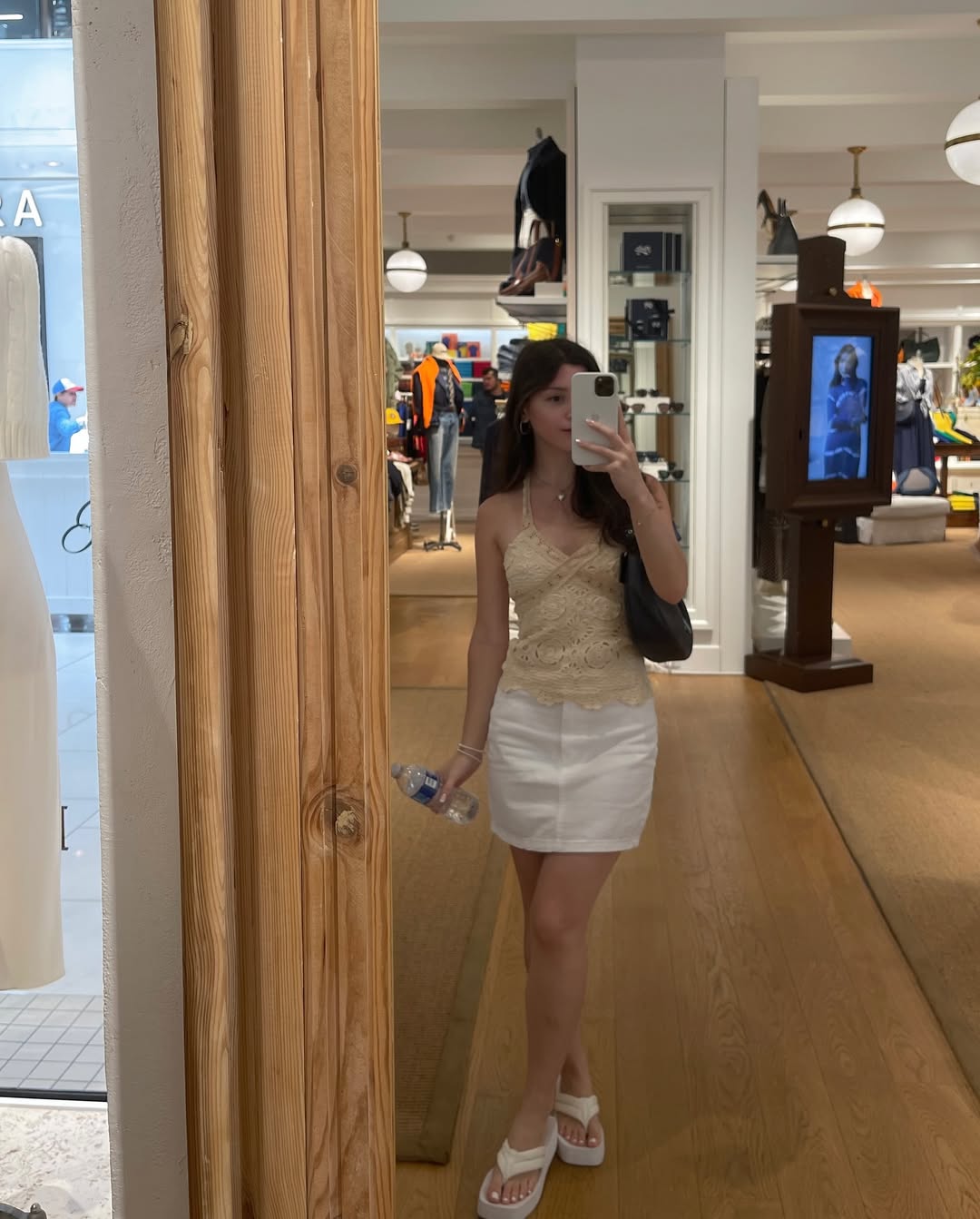 Skye ASMR posing in a sunny garden wearing a white halter top and beige skirt