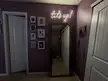 Female living space with purple walls, a neon sign saying 'up', a full-length mirror, and framed wall art.