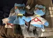 Two blue Build-A-Bear plush toys with orange eyes and grey limbs, one wearing a white shirt with a red circle.