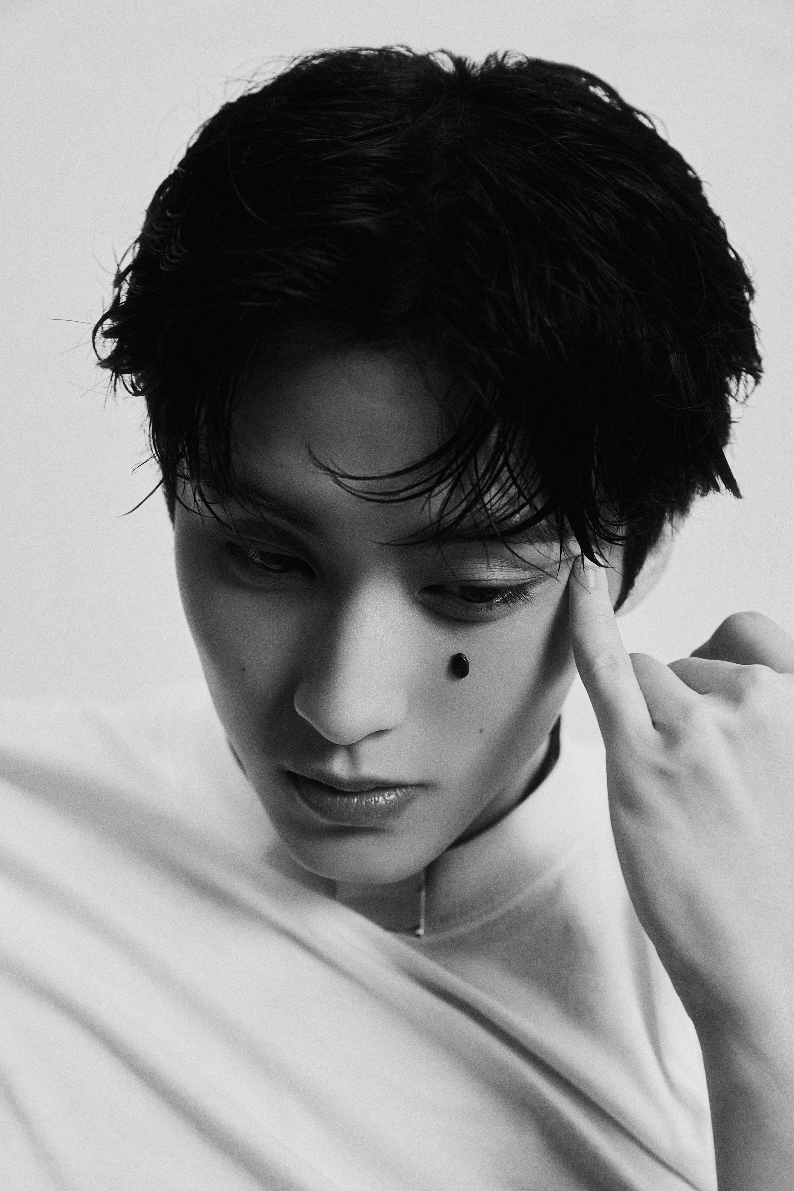 NCT Mark in a white t-shirt, black trousers, and black cap for The Firstfruit teaser