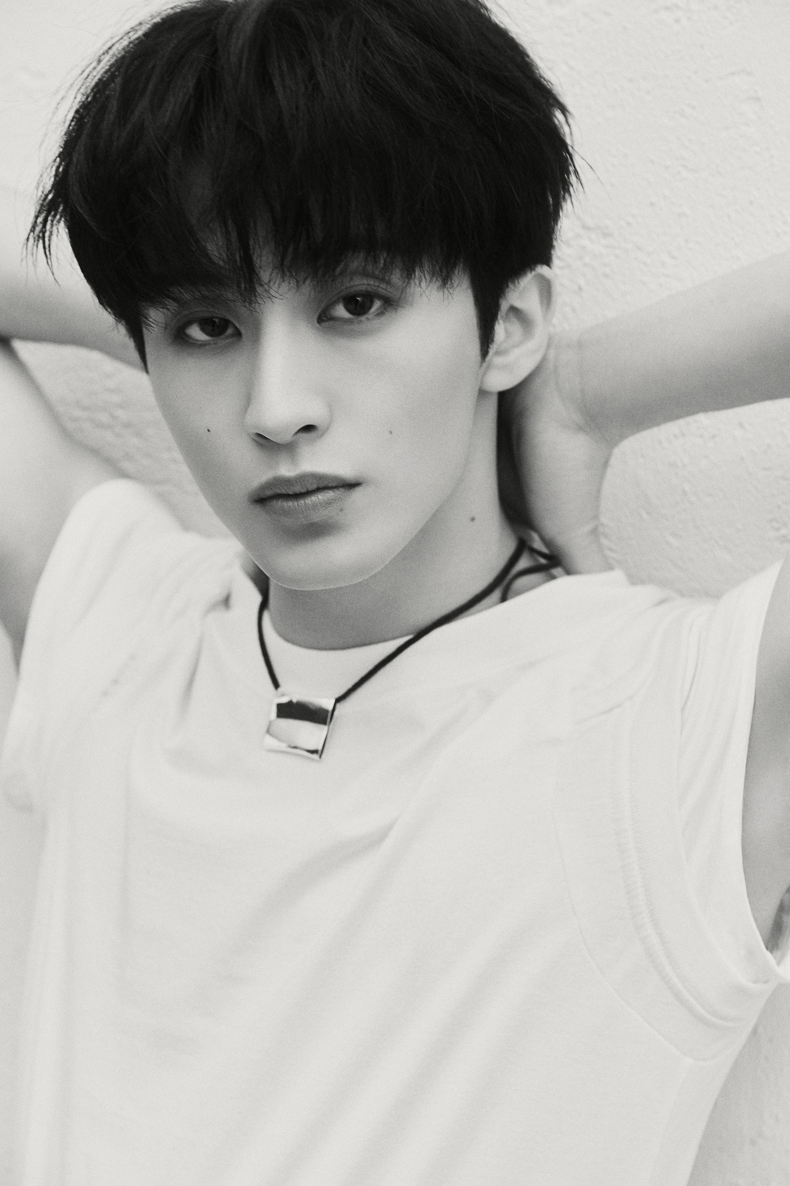NCT Mark in a white t-shirt, black trousers, and black cap for The Firstfruit teaser