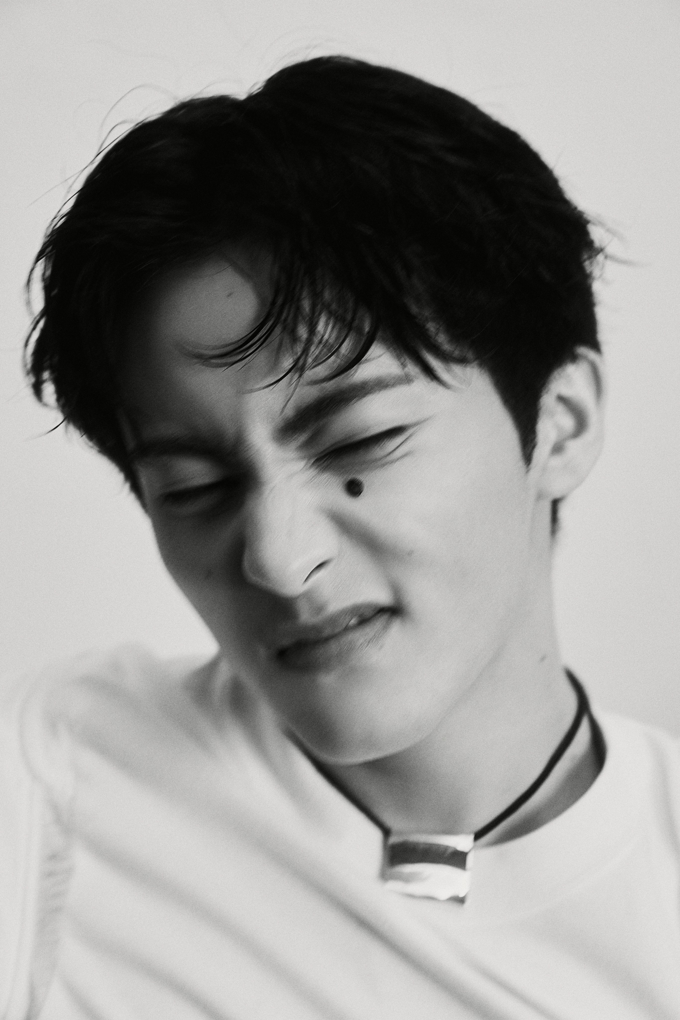 NCT Mark in a white t-shirt, black trousers, and black cap for The Firstfruit teaser