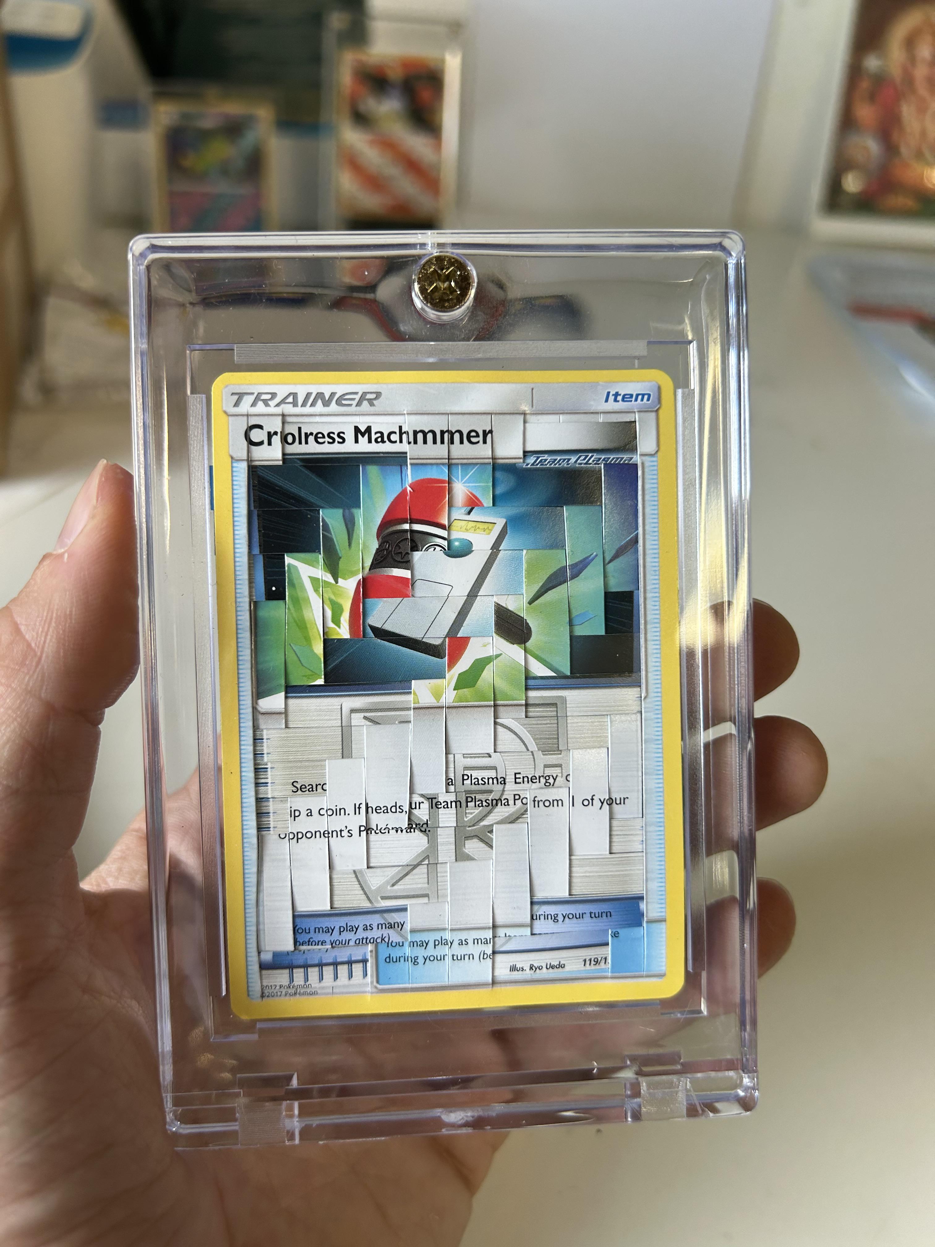 A person with pale skin holding a clear plastic case with a fragmented Pokémon weaving of a Colress Machmer card.