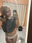 Blonde Asian femboy in a floral print top and white panties taking a mirror selfie in a bedroom