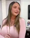 Busty blonde in a pink outfit dancing and laughing, showing a boob bounce in a living room.