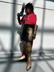 Vincent Valentine cosplay featuring a slender person in gold armor, a red cropped jacket, and a large black prop weapon