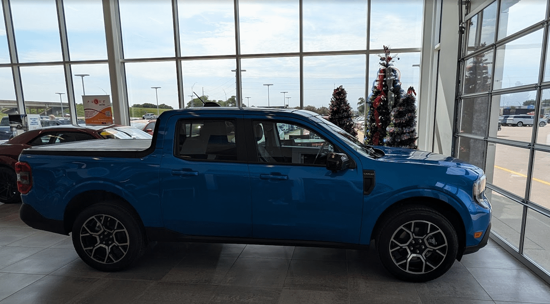 Blue Ford Maverick truck parked in a car showroom with Christmas trees