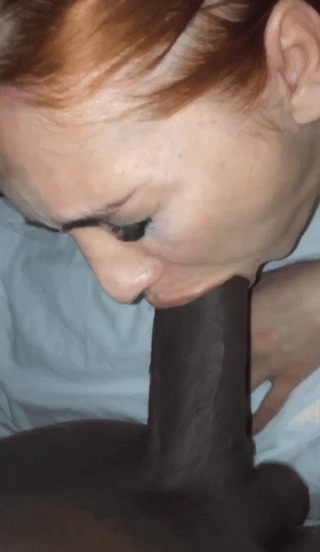 Redhead snowbunny performing a blowjob on a black man in a bedroom selfie video.