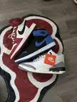 Nike sneakers in red, blue, and white colors resting on a patterned rug