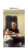 A man in a black t-shirt playing an electric guitar on a couch, pointing to the camera for a funny guitar meme.
