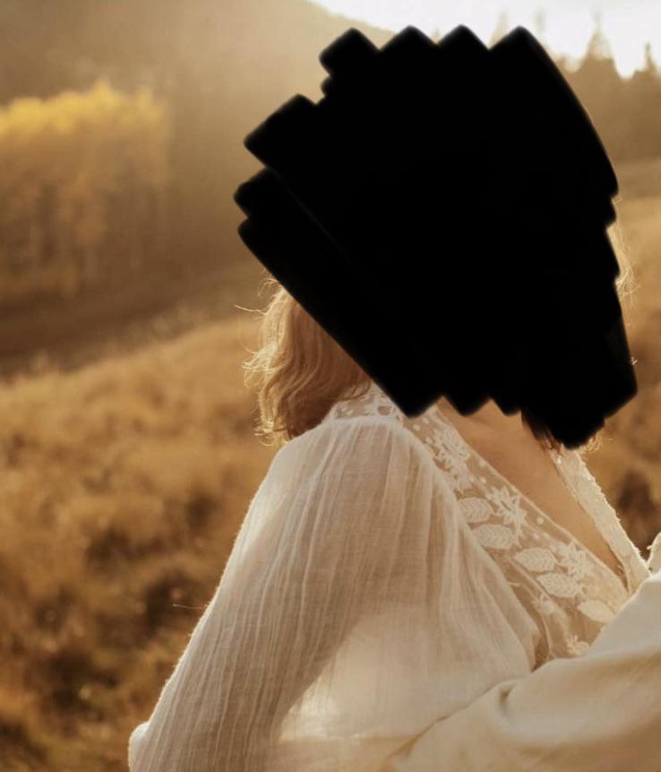 Woman in a white lace blouse and blue jeans embracing a man in an autumn field with mountains.
