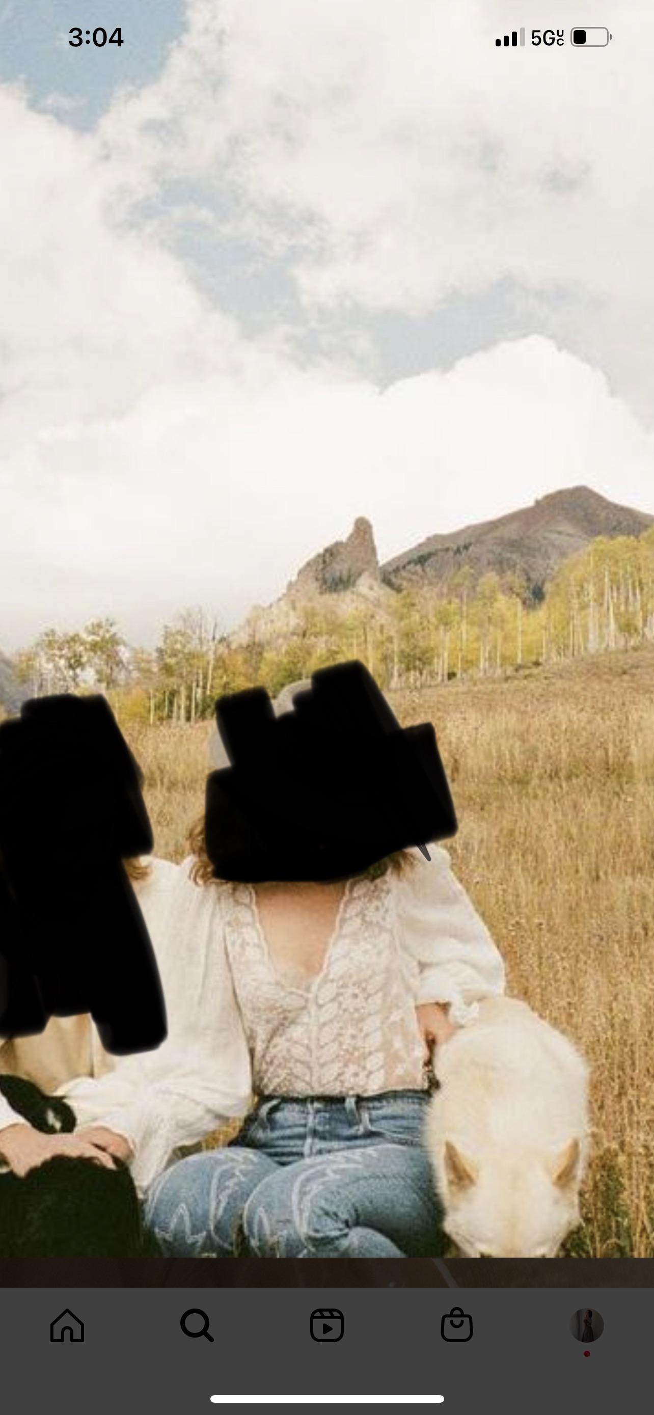 Woman in a white lace blouse and blue jeans embracing a man in an autumn field with mountains.
