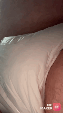 A man in a diaper lying in bed under a white sheet with a visible wet spot.