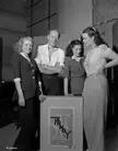 Australian actor Actor Cyril Ritchard (Captain Hook in Peter Pan (1945)) with three young women, presumably from the cast of The Winslow Boy (1948), listen to the Tannoy public address system.