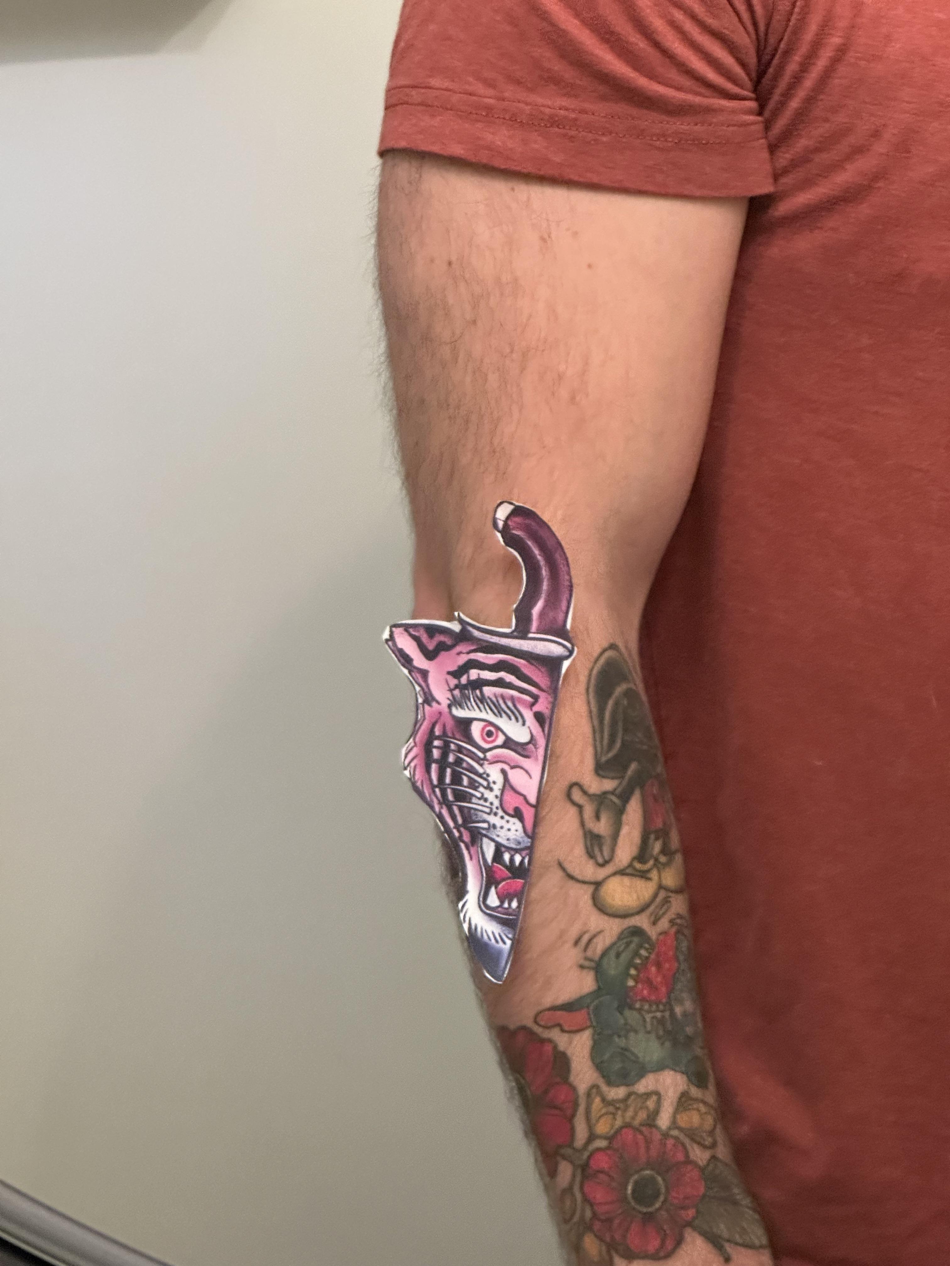 Traditional tattoo design of a tiger's face integrated into a curved knife blade on a beige background
