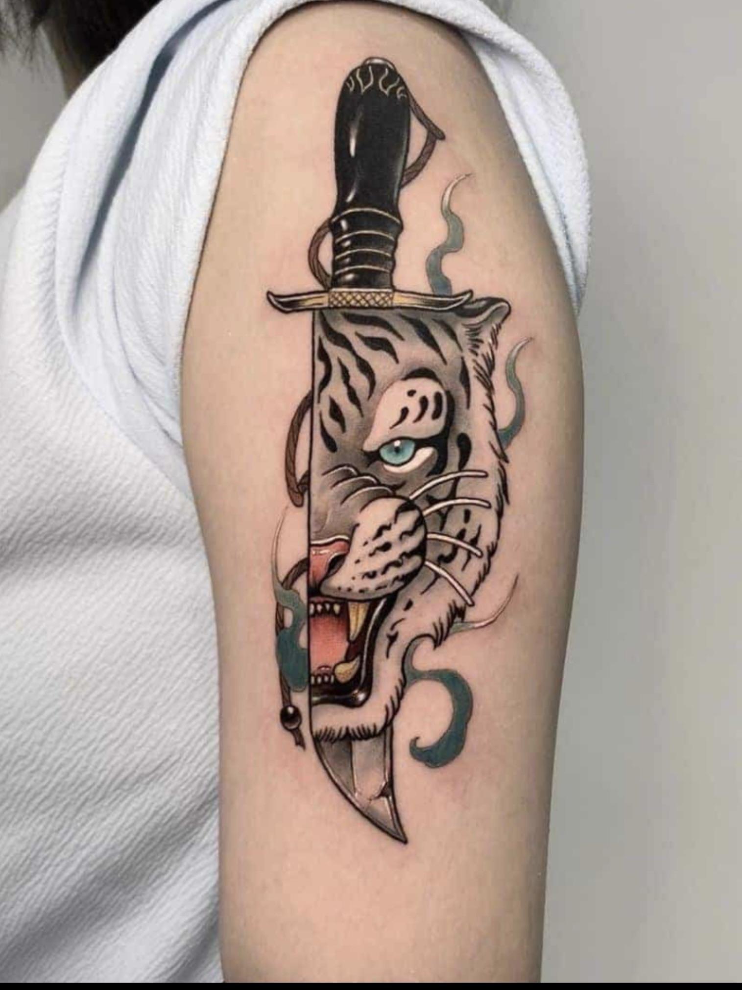 Traditional tattoo design of a tiger's face integrated into a curved knife blade on a beige background