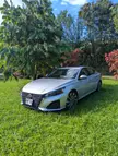 Silver Nissan sedan with license plate ZLK 286 parked on a green grassy lawn next to lush trees.