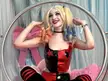 Harley Quinn from the HBO series in a red and black leather outfit sitting in a bubble chair with a pink cushion