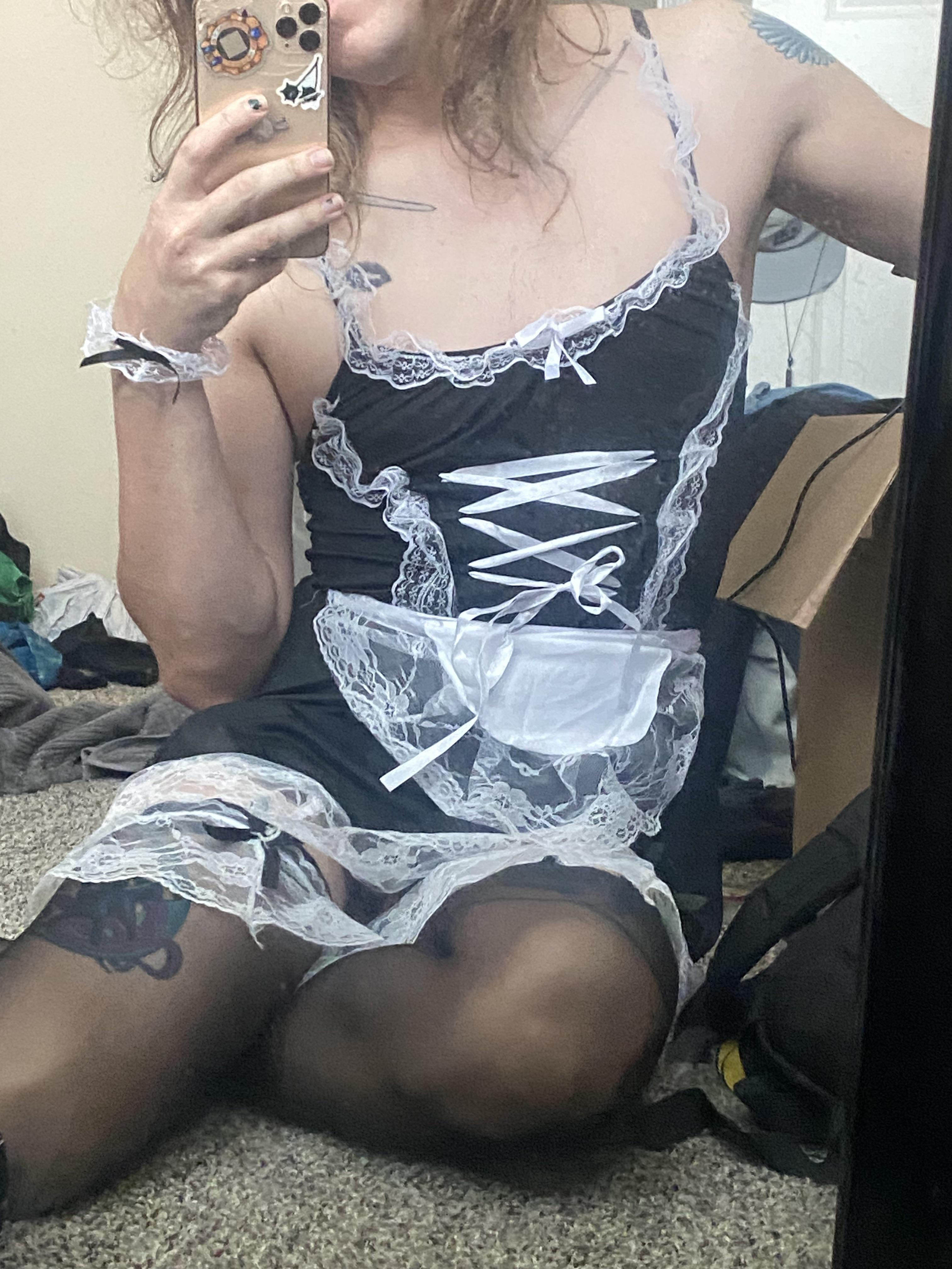 Trans woman and femboy in a black and white lace maid outfit and garter belt posing for a mirror selfie