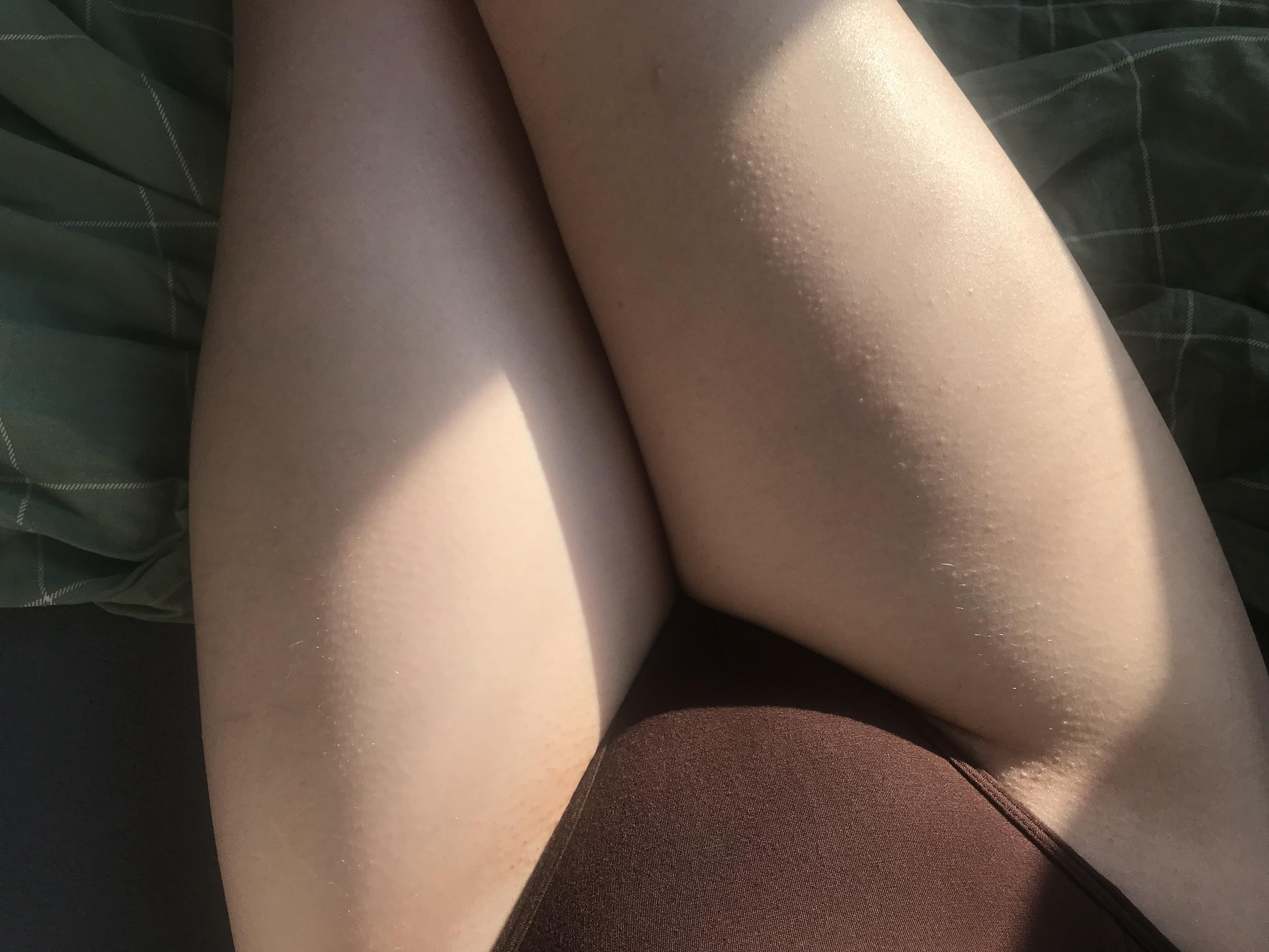 Trans girl and PAWG posing bent over on a bed in a brown thong, showing her ass from a back view.