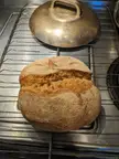 Homemade bread loaf on a metal cooling rack in a kitchen