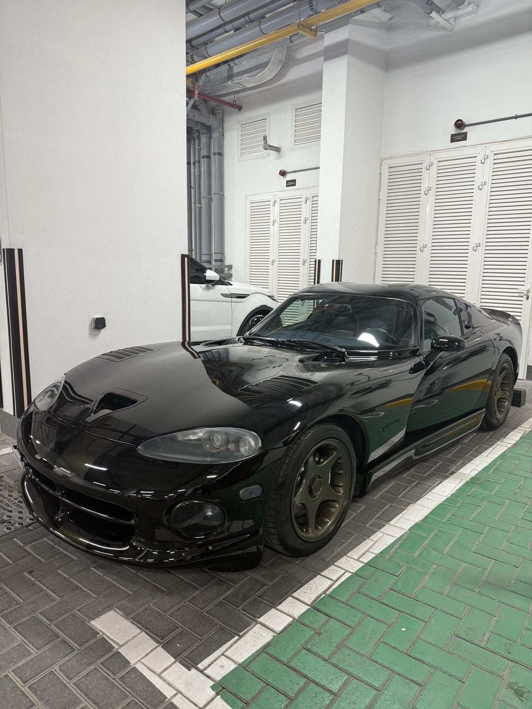 Viper GTS 1997 black sports car parked in a white garage next to a white vehicle